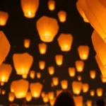 Globos de Cantoya iluminando el cielo nocturno en una celebración.