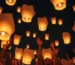 Grupo de personas lanzando globos de Cantoya al cielo nocturno.