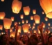 Globos de Cantoya iluminando el cielo nocturno en un evento festivo.